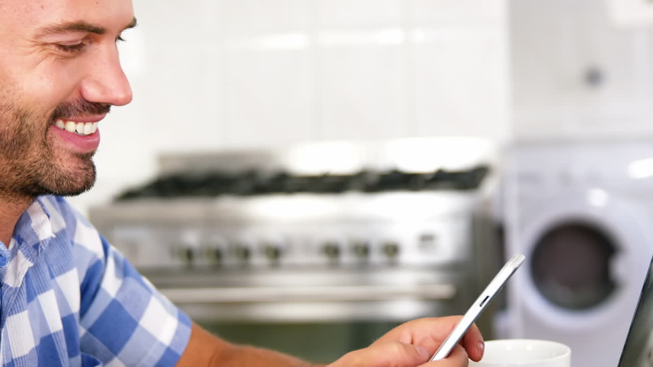 hombre feliz sentado en el sofá enviando mensajes de texto en el teléfono