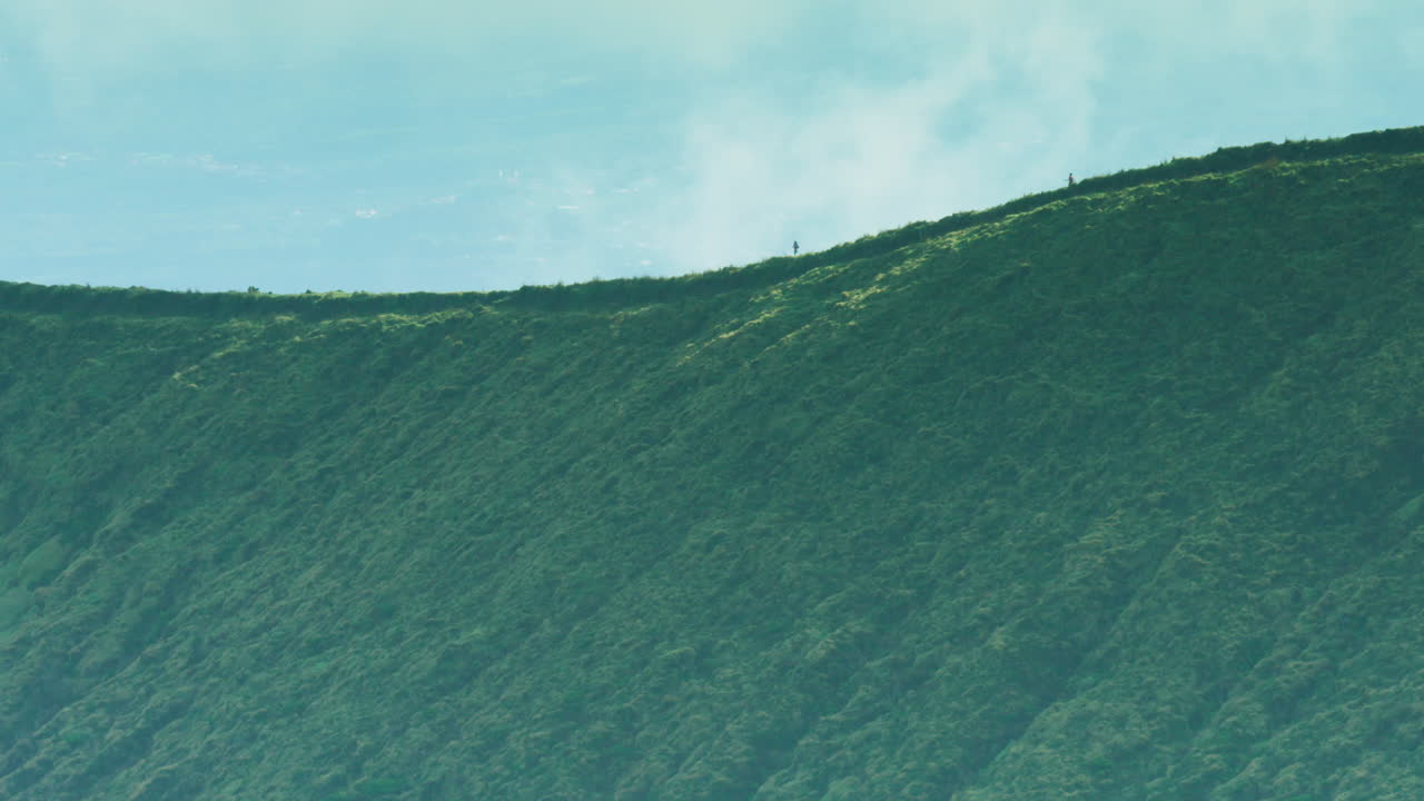 능선을 따라 걷는 두 명의 조깅하는 사람의 긴 렌즈 샷