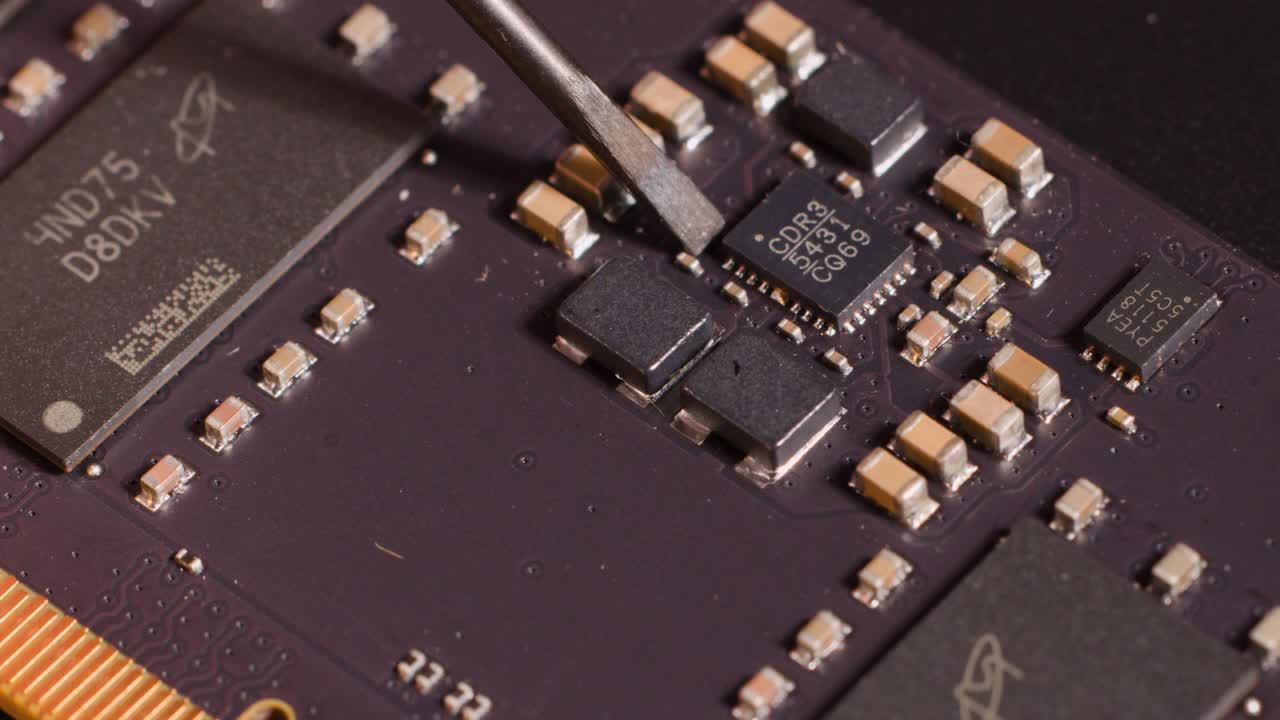 Macro view of a metal tool carefully inspecting electronic components on a purple motherboard