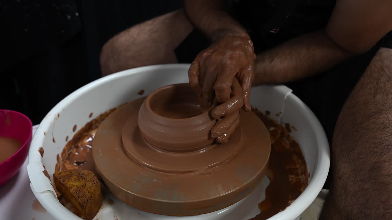 Ceramista uomo che utilizza un tornio da vasaio per dimostrare il movimento di apertura base di una palla di argilla, artigianato tradizionale in ceramica