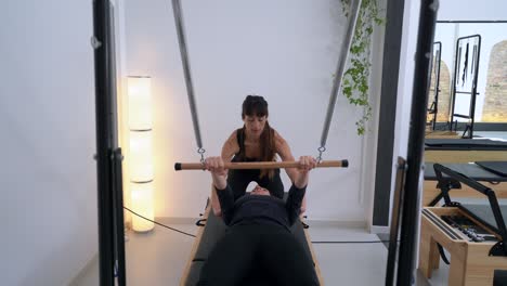 woman doing exercises on pilates reformer with instructor