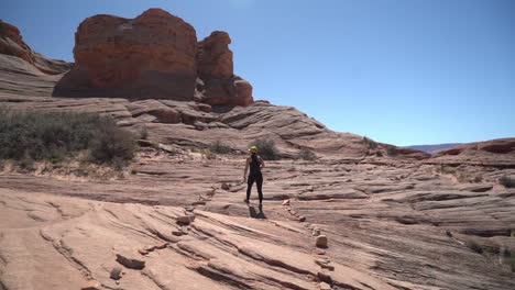 back view of woman walking alone on sandstone hill on hot sunny day, slow motion