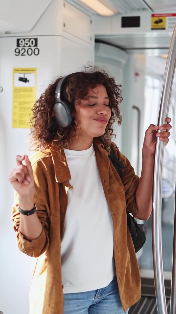 Giovane donna felice che ascolta musica con le cuffie su un treno
