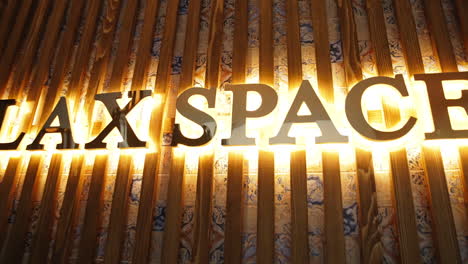 signboard on the wall with beautiful golden letters lit brightly from behind. name brand of a spa resort centre on the wooden panels.
