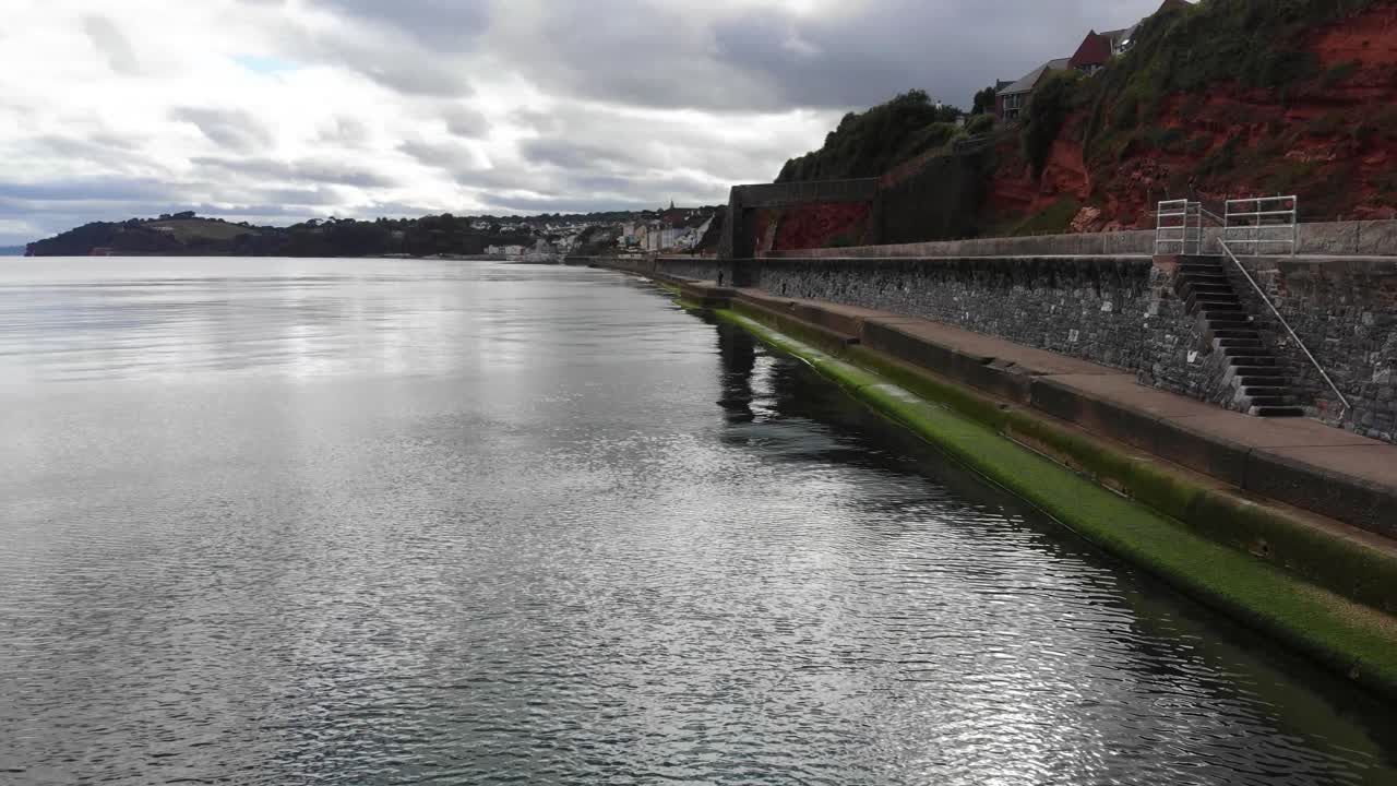 Coastline view showcasing seawall, tranquil waters, and distinctive geography of Dawlish, Devon.