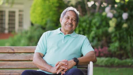 Video-of-happy-biracial-senior-man-sitting-on-bench-in-garden