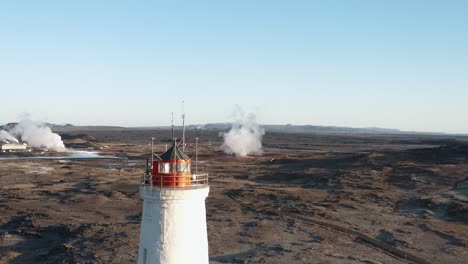 torre del faro rojo y blanco con paisaje volcánico en el fondo, antena