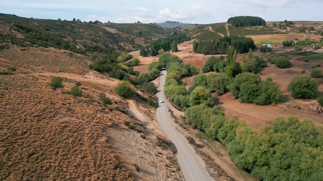Fremadgående flyvning over en snoet grusvej gennem bølgende bakker og dal. Liucura, Lonquimay, Chile
