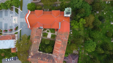 View-from-above-red-roof-of-house-tower-and-garden-with-green-trees,-Szombathely,-Hungary