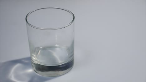 derramando leite em um copo. leite branco enchendo um copo transparente. leite derramando na frente de um fundo branco