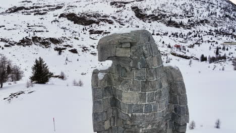 águila escultura de piedra en el paso de simplon con en el fondo los altos alpes suizos cubiertos de nieve