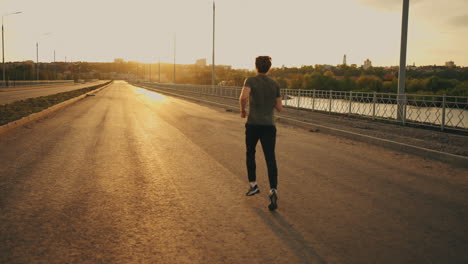 ein männlicher jogger trainiert im sommermorgen im freien. rücksicht auf einen sportlichen mann, der auf der straße läuft