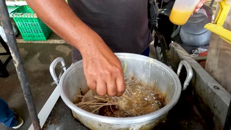 unrecognizable man cooks egg meatball satay in metal pot, close view