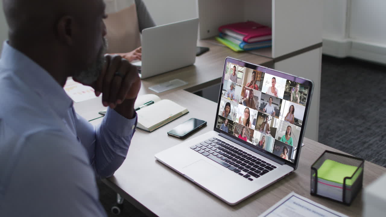 African american senior man having a video conference with colleagues on laptop at office