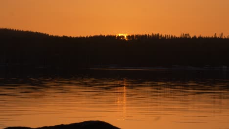 River-bank-Time-lapse-of-golden-sun-setting-behind-dark-alpine-hills