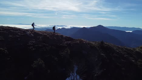 Drone-footage-of-two-hikers-walking-on-the-edge-in-the-mountains