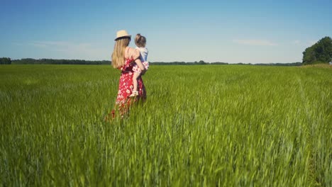 Cam-Tracking-Mom-wearing-summer-hat-and-dress-sunglasses-walks-across-an-endless-field