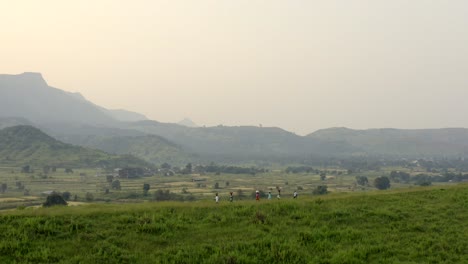 people carrying and balancing bag on their head walking in the green hills at sunrise in karjat near mumbai city in india