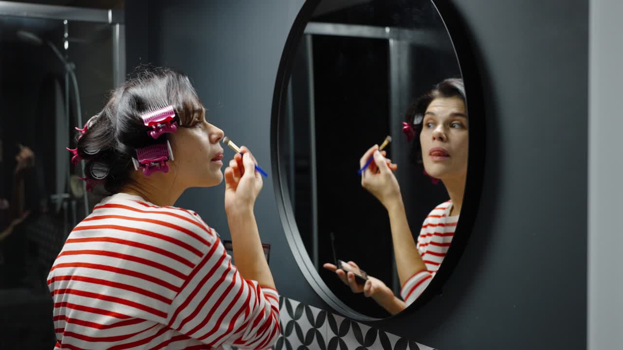 mujer aplicando maquillaje frente al espejo del baño