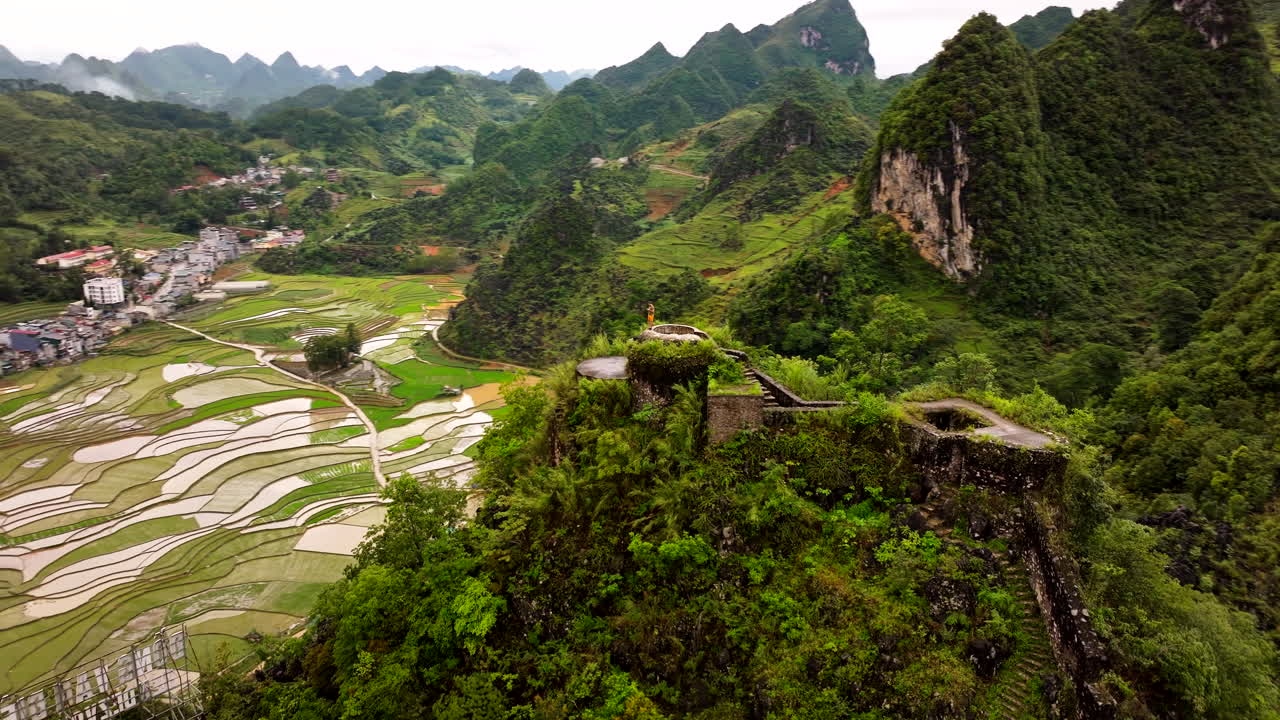 Aerial orbit around Dong Van French Fortress with male traveller at viewpoint