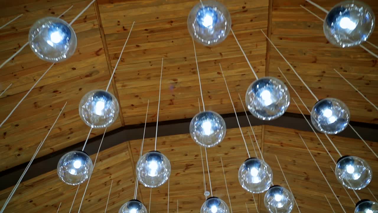 Cozy ceiling with many crystal small balls. Round light bulbs hanging on white wires. Modern design of shiny light lamps.