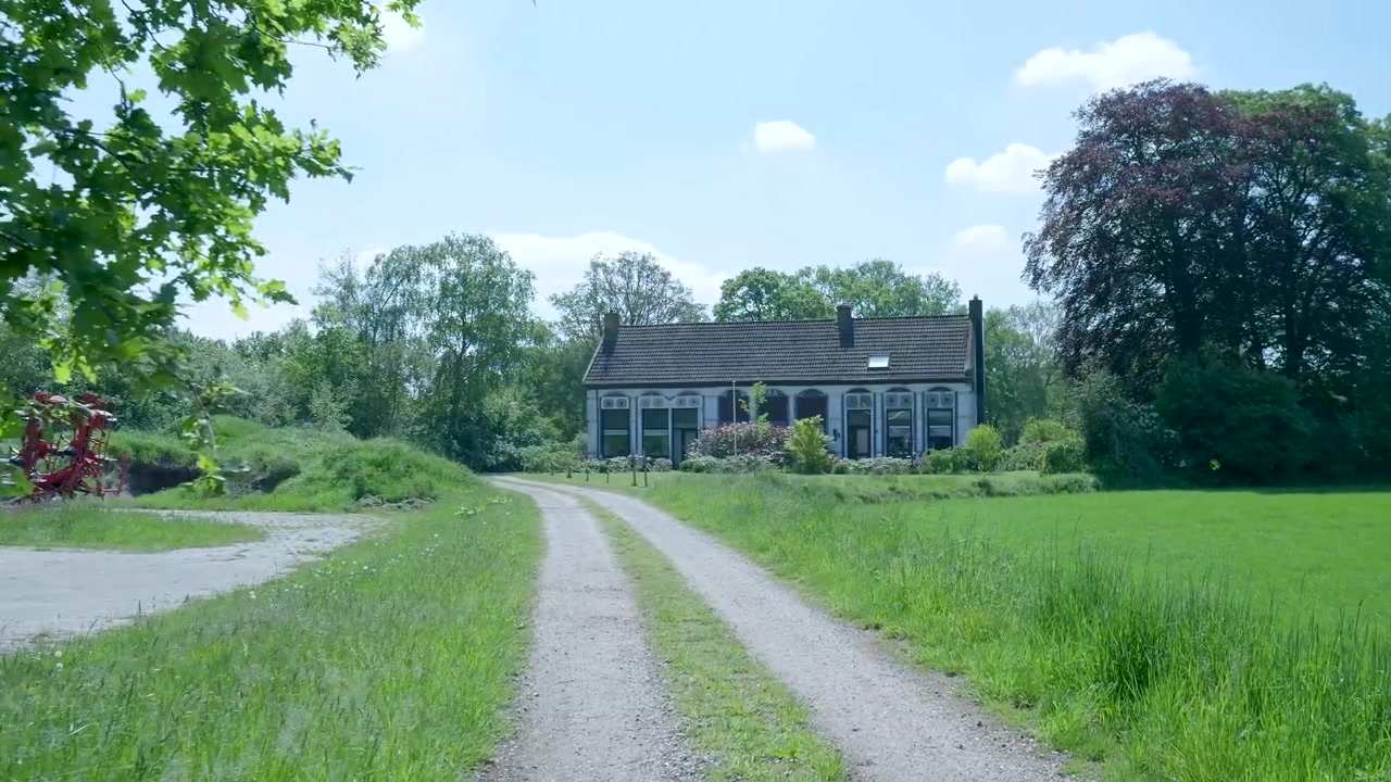 Traditionel hollandsk bondegård omgivet af frodige grønne marker og træer