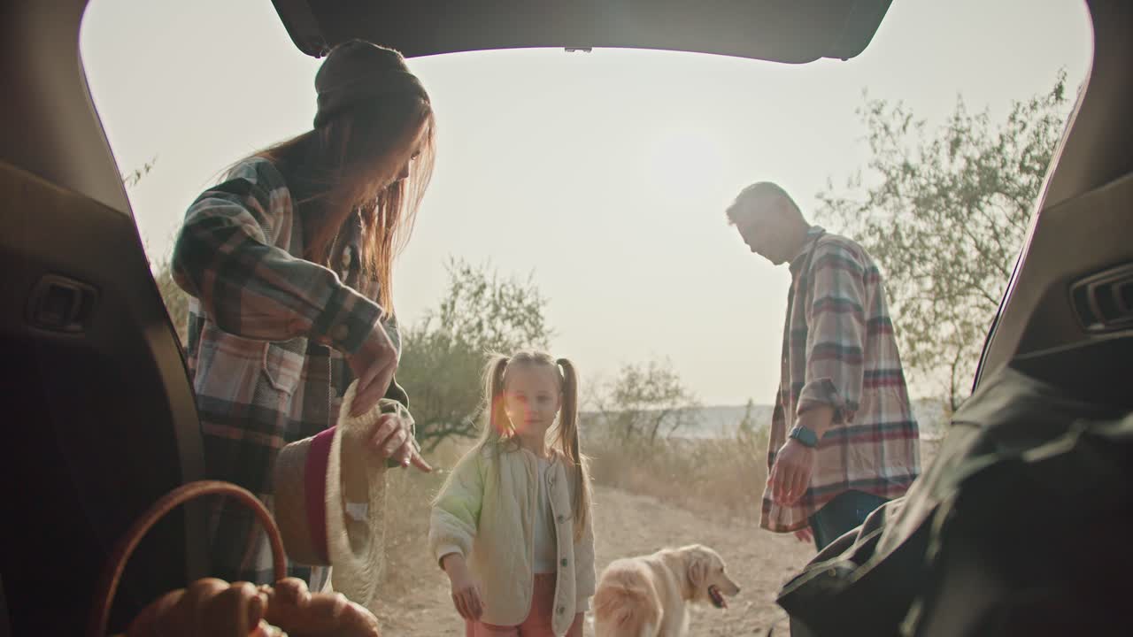 커다란 크림색 개가 트크 밖으로 달려 나갔고, 그 트크를 은 셔츠를 입은 회색 머리카락의 남자가 그의 아내와 초록색 셔츠와 작은 딸을 입은 갈색 여자친구와 함께 열고 여름에 건조한 풀로 된 길을 따라 피크닉에 갔습니다.