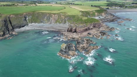 Aislada-Playa-De-Tra-Na-Mbno-En-La-Costa-De-Cobre-Waterford-Irlanda-Con-Exuberantes-Tierras-De-Cultivo-Y-En-La-Playa-Bunmahon-Derecha-En-Un-Cálido-Día-De-Julio