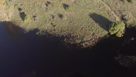 AERIAL-Reverse-Shot-of-a-DAM-in-a-Green-Valley-with-Housing-in-the-BACK