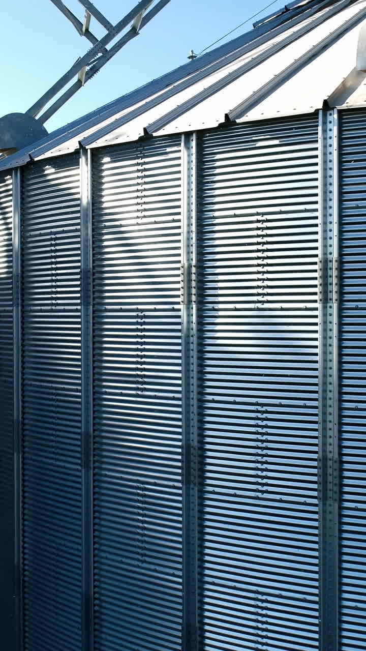 Large storage tanks in nature. Grain terminals. Industrial metal bins for agribusiness. Modern warehouse. Close-up. Aerial view. Vertical video