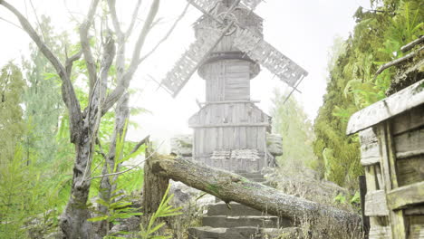 wooden windmill surrounded by greenery on a foggy day in a rural setting