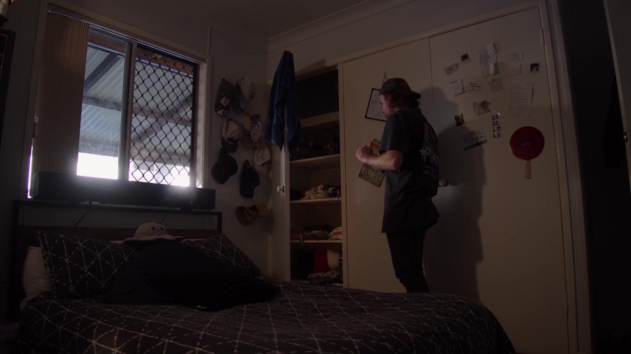 Grande plano cinematográfico 4K de um homem ativando uma luz de armário com sensor de movimento com um gesto de mão antes de se levantar e fazer um sinal de positivo com os dois polegares em um quarto.