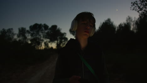 adolescente escuchando música en el bosque por la noche