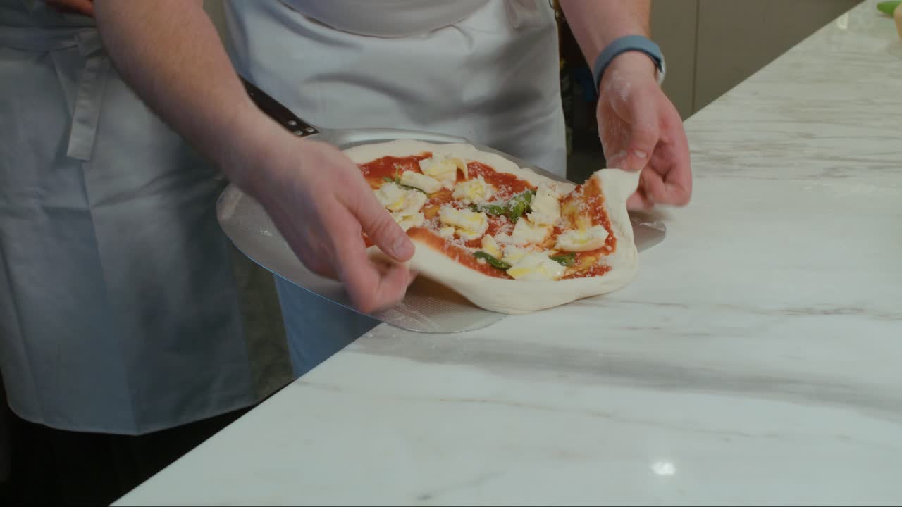 Stretching raw pizza and pulling it onto the shovel
