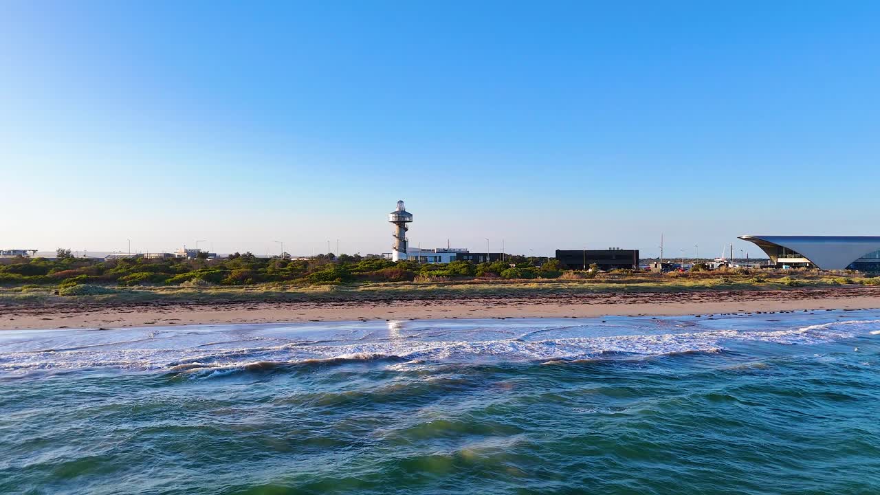 Aerial view of Bellarine Peninsula's coastline with a lighthouse, captured in bright daylight, showcasing natural beauty and serene waters