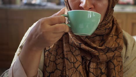 mujer en hijab bebiendo café en una cafetería