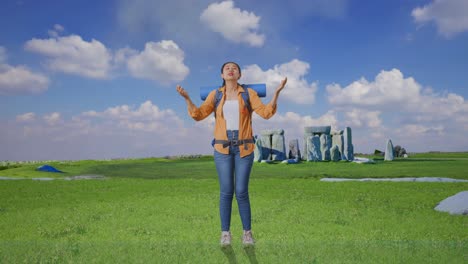 full body of asian female hiker with mountaineering backpack spreading arms enjoy looking the view around while traveling in stonehenge