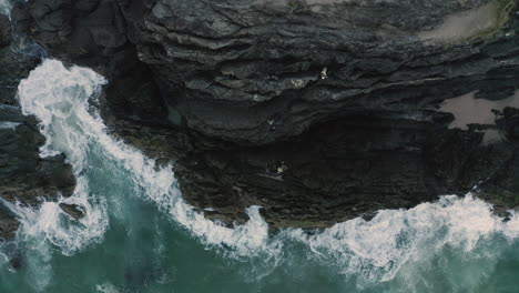 4k top view drone shot of hikers climbing on a rock side on a small island close to byron bay, australia