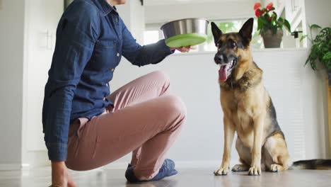 mujer caucásica alimentando a su perro en la sala de estar en casa