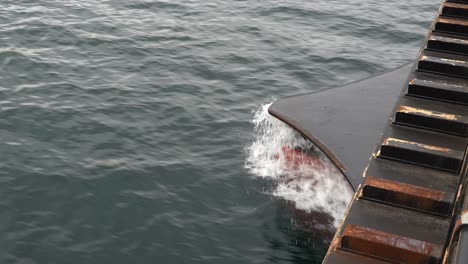 front bow of passenger ship is penetrating through sea with water splashing around while moving forward - close up of bow