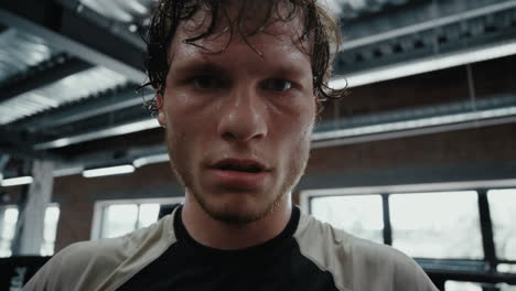 young fighter staring at lens in fitness center. kickboxer showing aggression