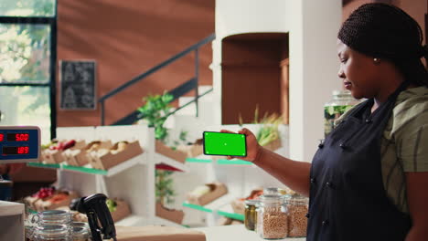 storekeeper holds mobile phone with greenscreen display