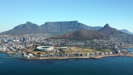 Estadio-De-Ciudad-Del-Cabo-En-La-Costa-Del-Mar-En-Ciudad-Del-Cabo,-Sudáfrica-Con-La-Colina-De-La-Señal-Y-El-Parque-Nacional-De-La-Montaña-De-La-Mesa-En-Segundo-Plano