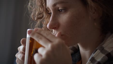 Close-up-of-caucasian-red-head-woman-cold-and-drinking-hot-tea-in-the-living-room