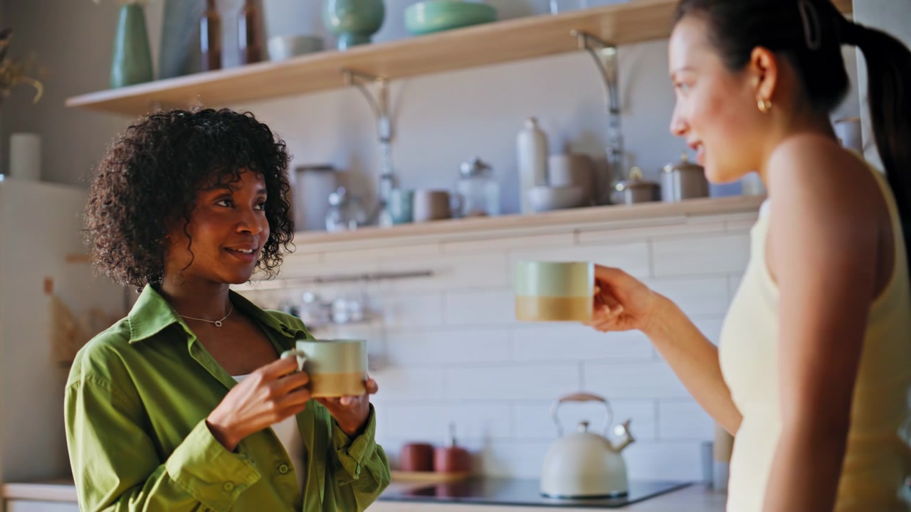 Amici multietnici che bevono caffè e parlano in cucina. Donne felici che chiacchierano a casa.