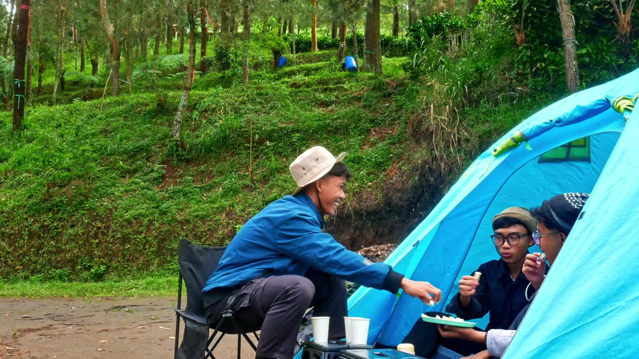 Friends enjoying camping adventure in lush green forest with blue tent and happy vibes