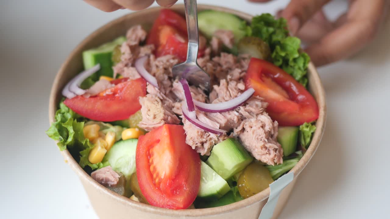 cerca de una persona comiendo una ensalada de atún en un cuenco