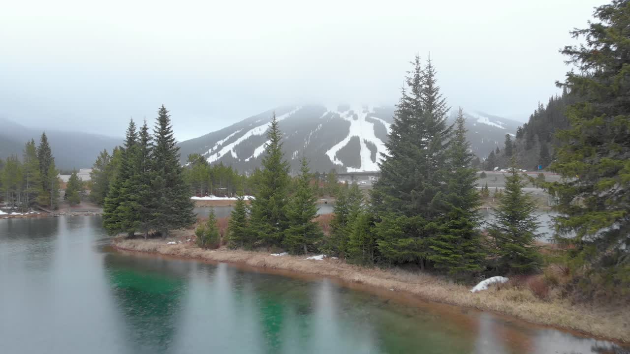 lluvias de nieve en un estanque turquesa en colorado con el resort de copper mountain en el fondo