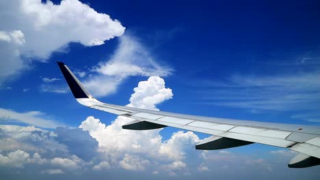 view from windows of commercial airplane wing maneuver with cloudy blue sky