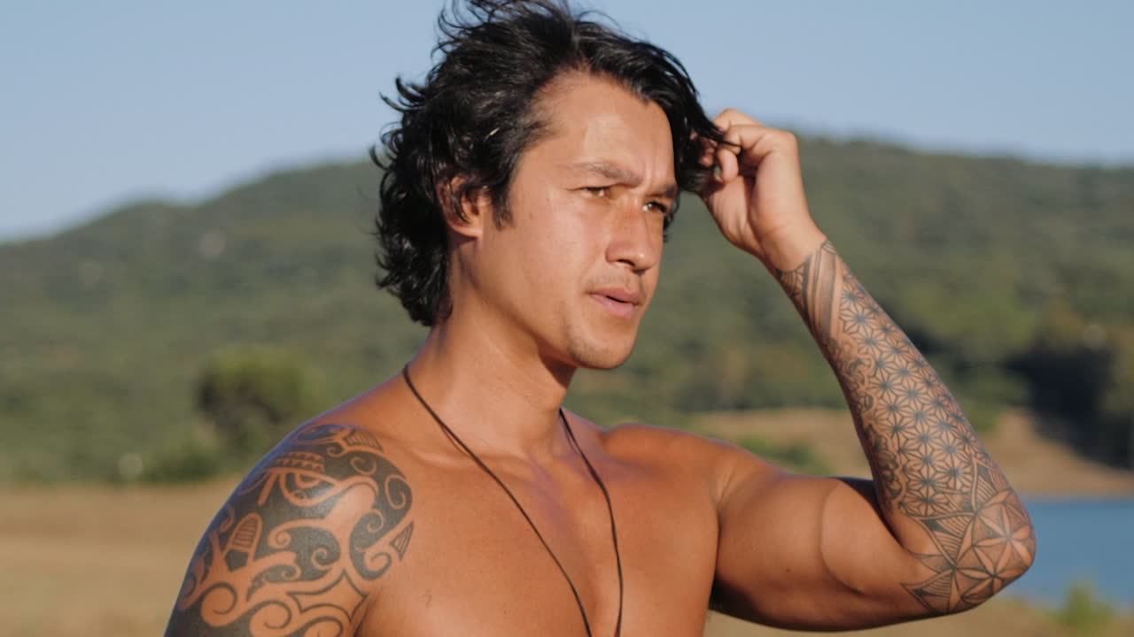 더운 여름날 머리를 빗고 있는 셔츠 없는 문신을 한 남자 - 클로즈업